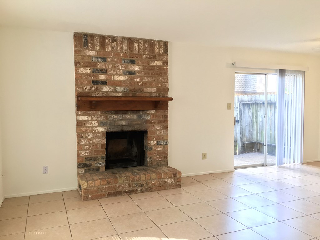 the living room has a brick fireplace and a tile floor