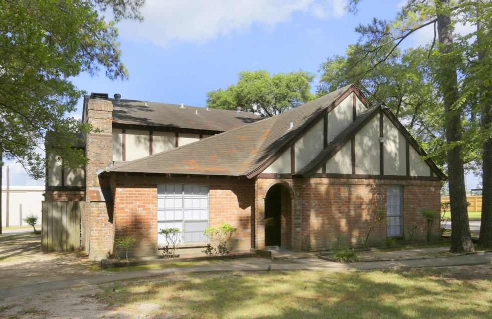 the front of a brick house with a garage and trees