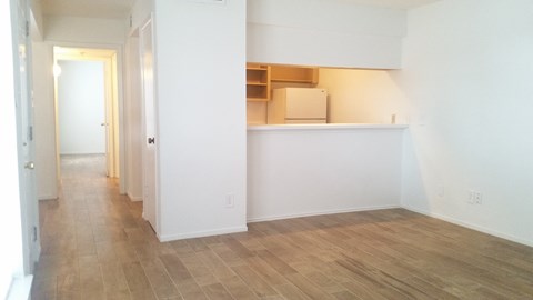 an empty living room with white walls and a wood floor