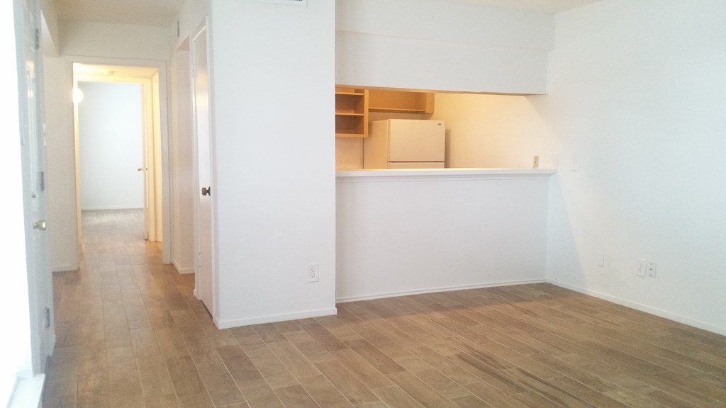 an empty living room with white walls and a wood floor