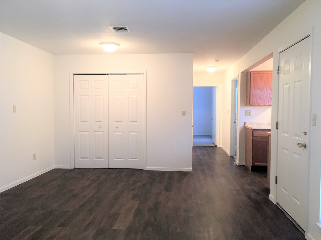 an empty living room with a white door and a bathroom