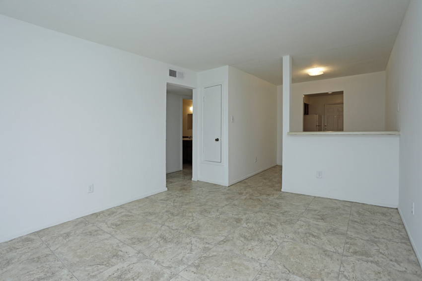 an empty living room with white walls and a tile floor