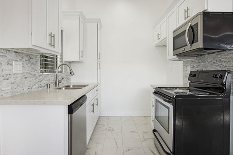 a white kitchen with black appliances and white cabinets