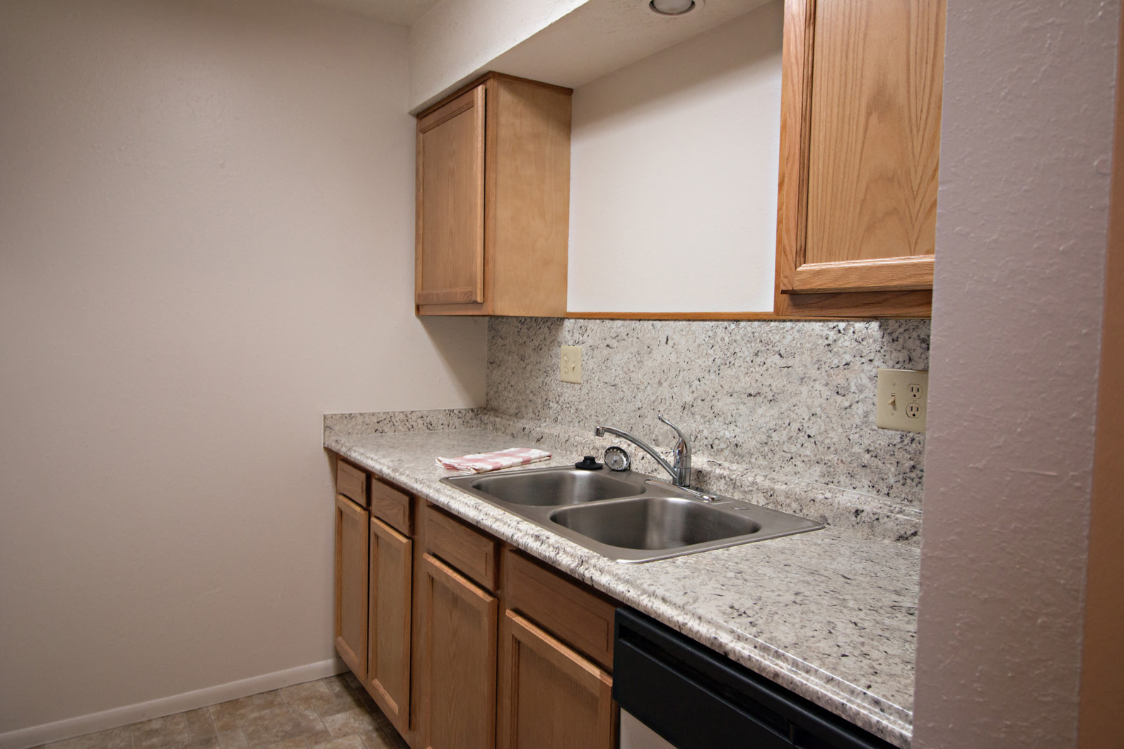 an empty kitchen with a sink and wooden cabinets