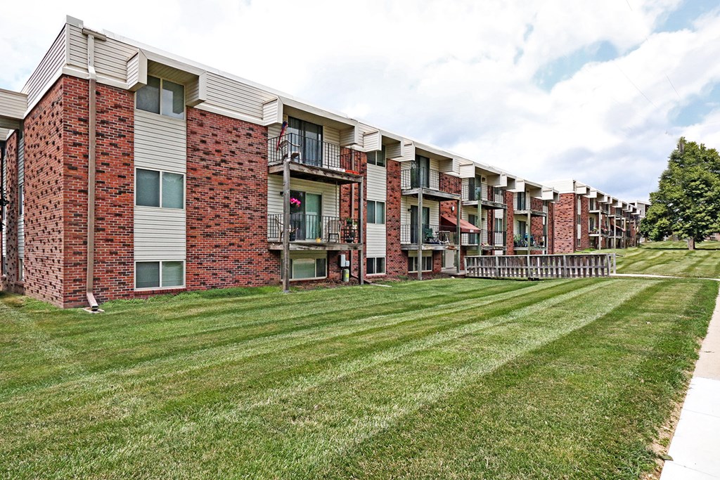 an exterior view of an apartment building with a lawn
