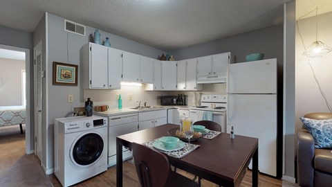 a kitchen with a washer and dryer and a dining room with a table