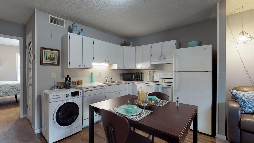 a kitchen with a washer and dryer and a dining room with a table