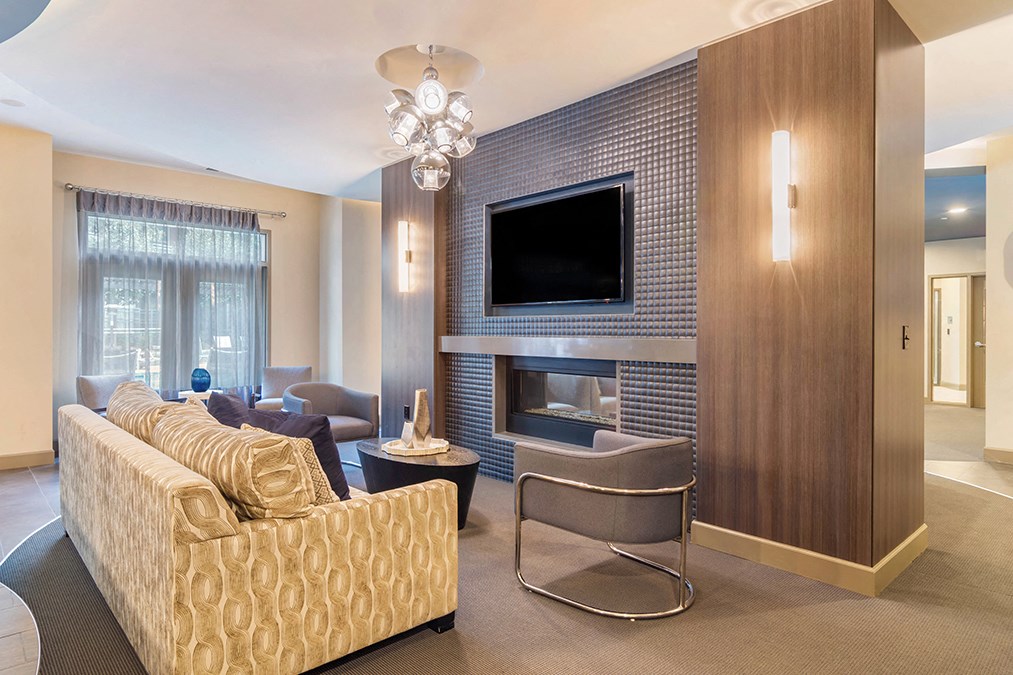 A modern living room with a yellow sofa and a television mounted on the wall.