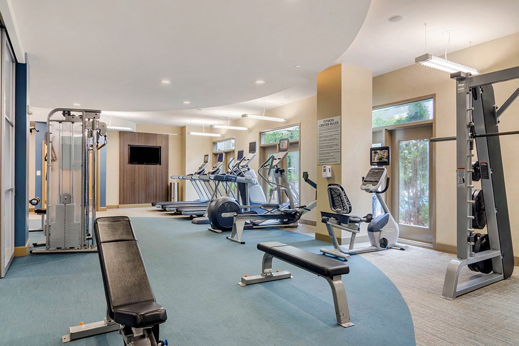 A gym with a variety of equipment including treadmills, weights, and exercise machines.