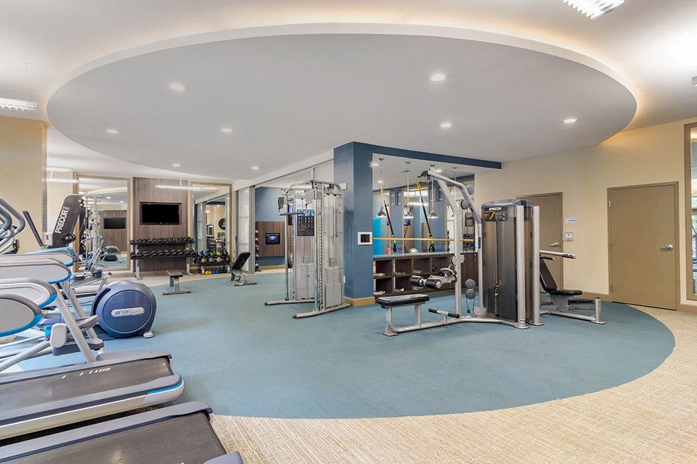 A gym with a variety of equipment including treadmills, weights, and exercise machines.