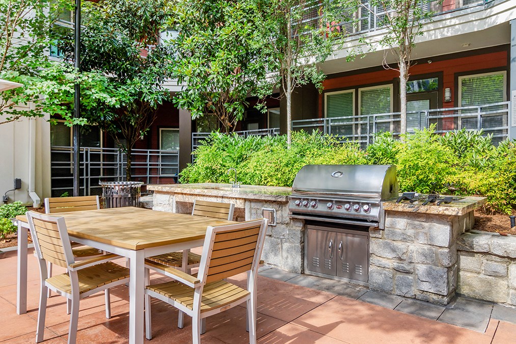 A patio with a table and chairs and a grill.