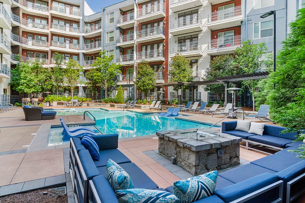 A large outdoor pool area with a stone fountain and lounge chairs.