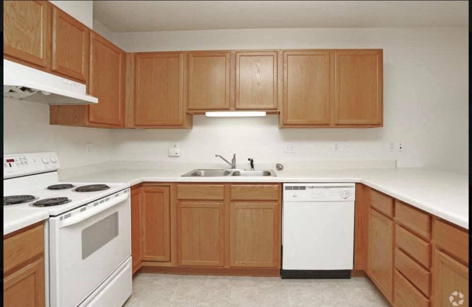 an empty kitchen with wooden cabinets and white appliances