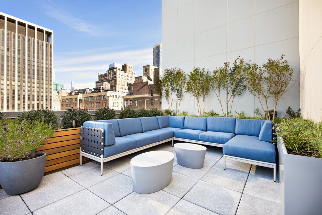a rooftop patio with blue couches and tables and plants