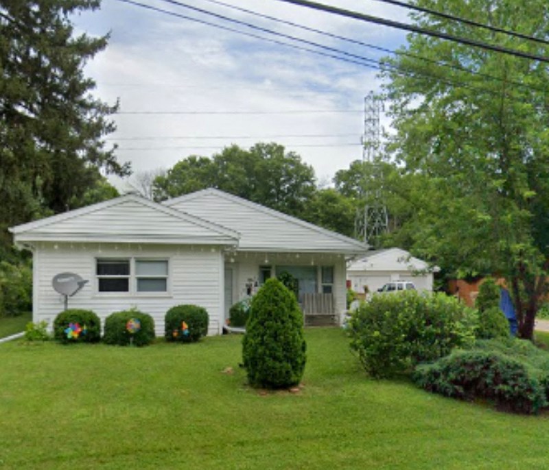 a white house with a yard and some bushes
