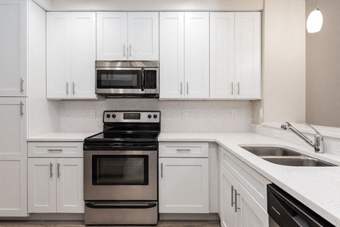 a white kitchen with stainless steel appliances and white cabinets