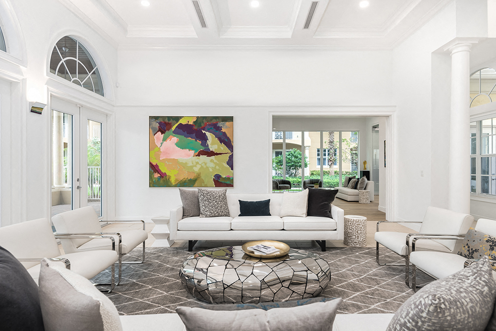 a living room with white furniture and a large painting on the wall