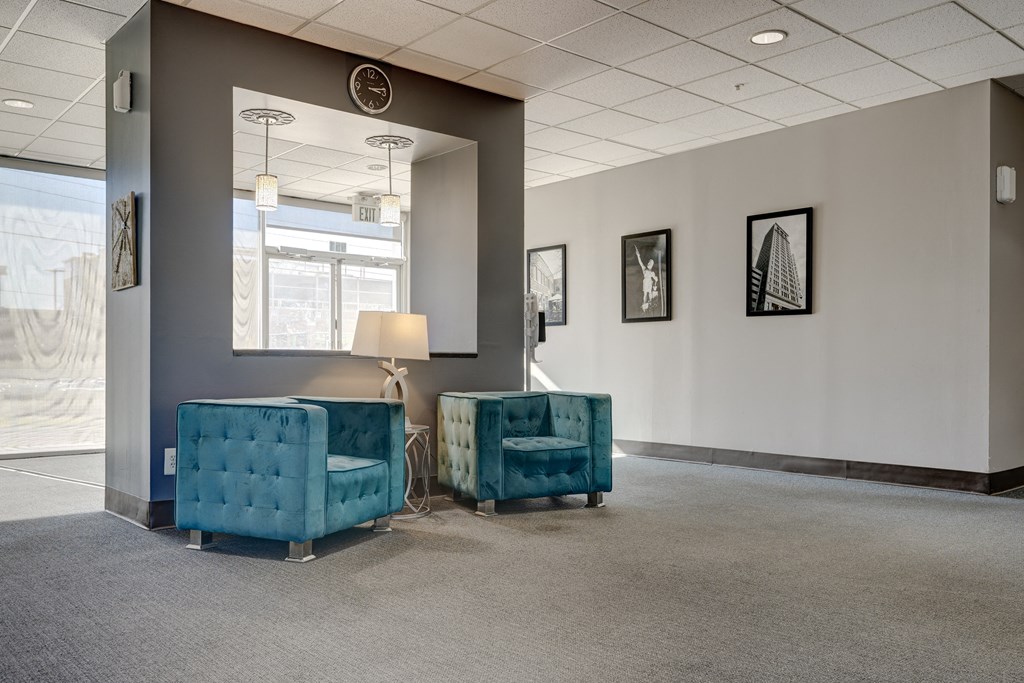 a waiting room with two blue chairs and a lamp and a window