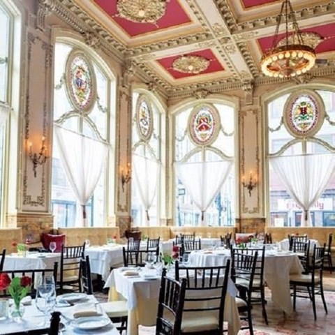 a dining room with tables and chairs and large windows