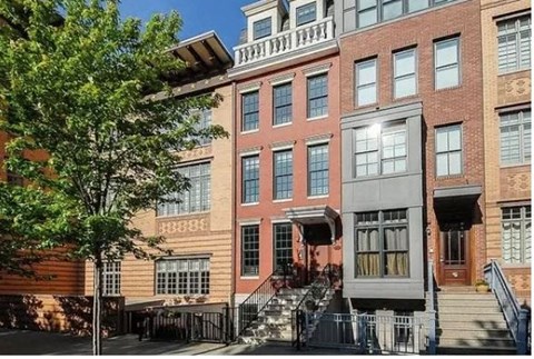 the front of a brick building with stairs and a tree