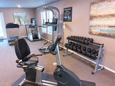 a gym with weights and cardio equipment at the enclave at university crossings apartments