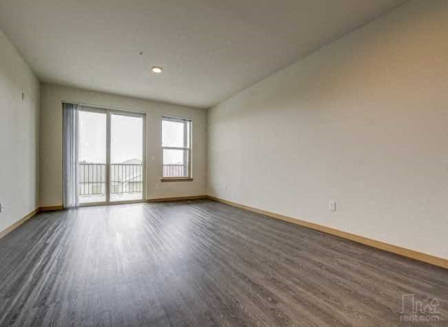an empty living room with wood floors and a sliding glass door