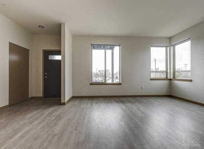an empty living room with wood floors and windows