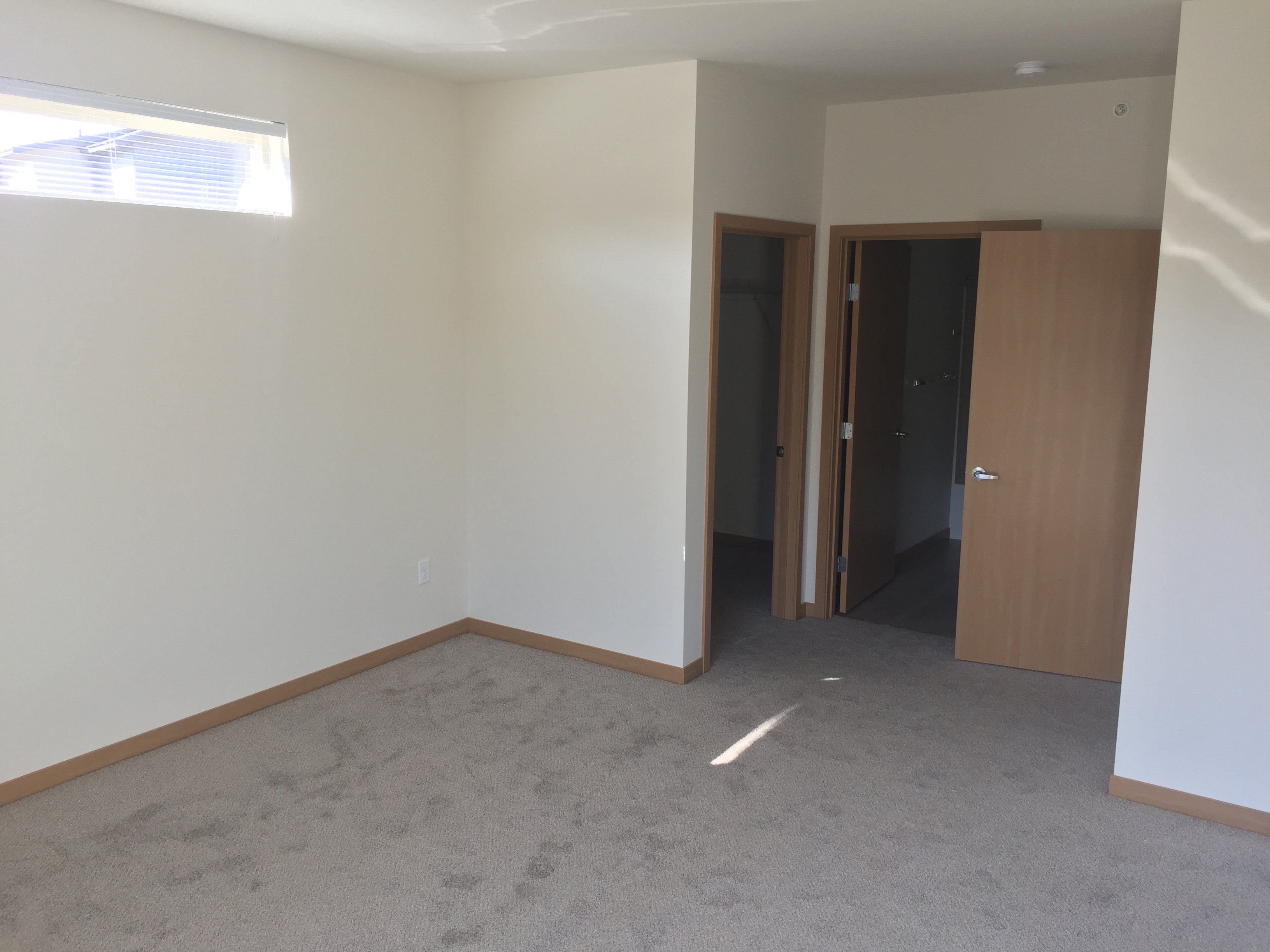 an empty living room with a door to a hallway and a closet