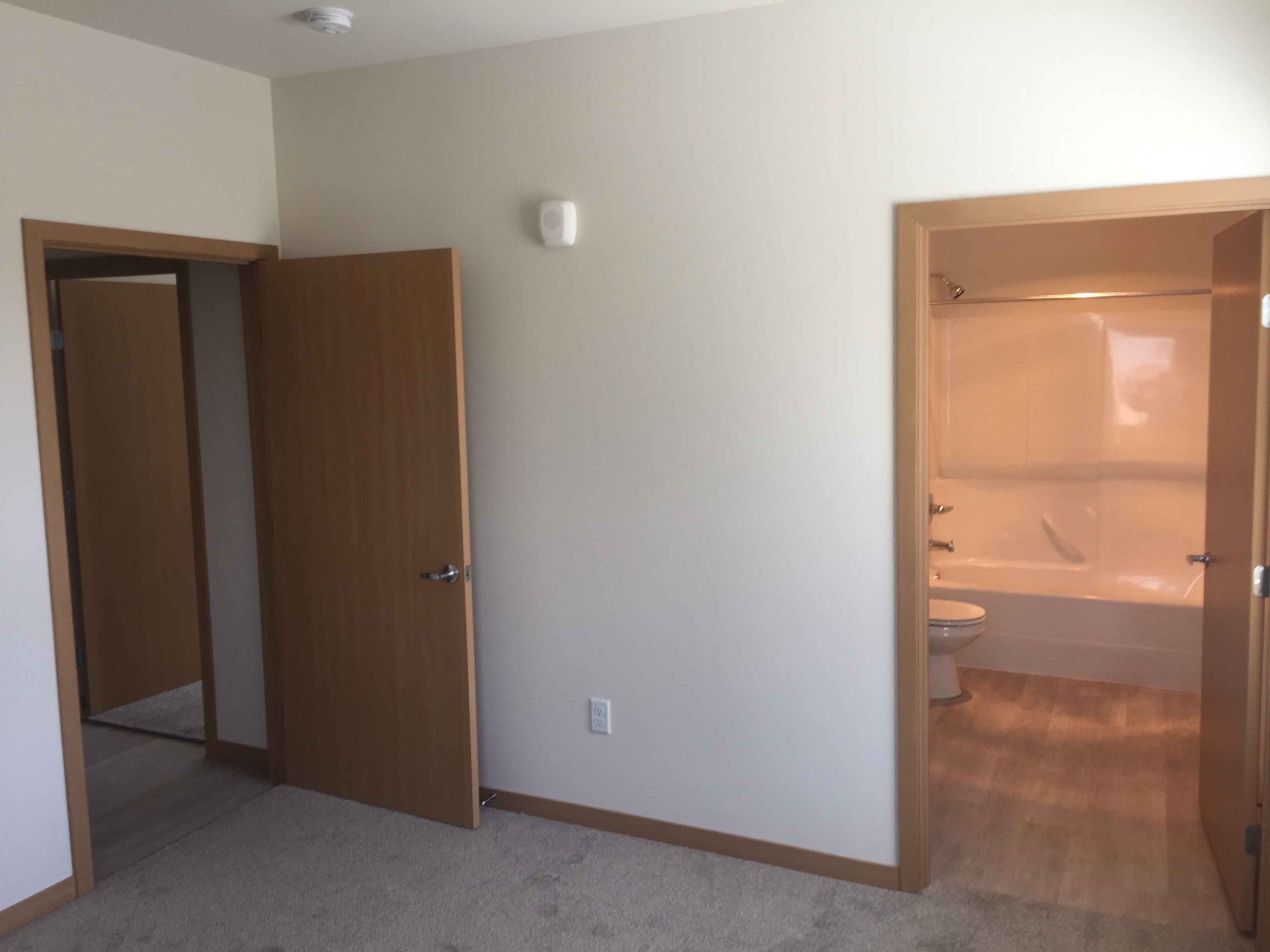 an empty bathroom with two doors and a toilet