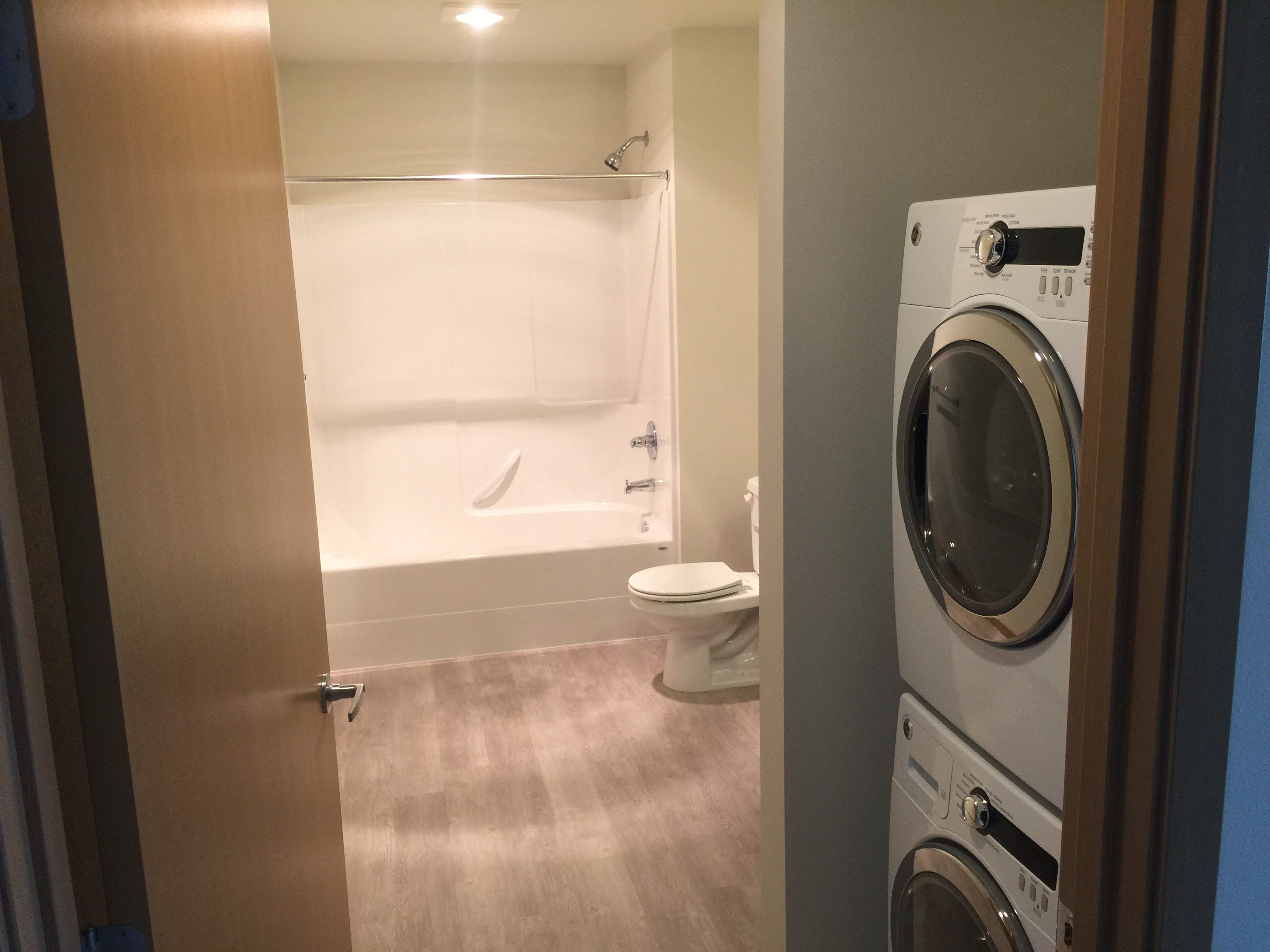 a bathroom with a washing machine and a toilet and a bath tub