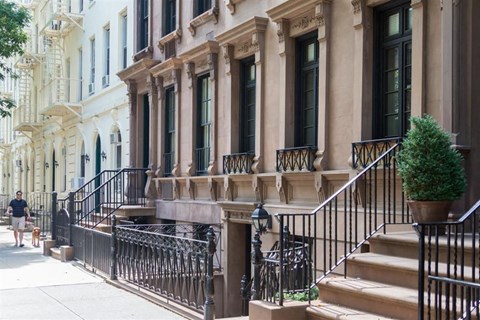 a man walking down the sidewalk in front of a building