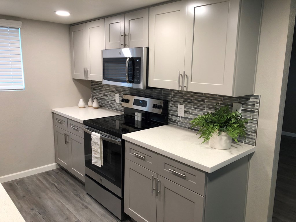 a kitchen with white cabinets and black appliances