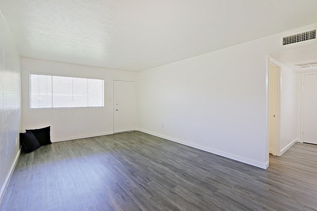 an empty living room with wood flooring and a window