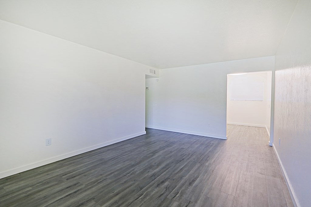 an empty living room with white walls and wood floors