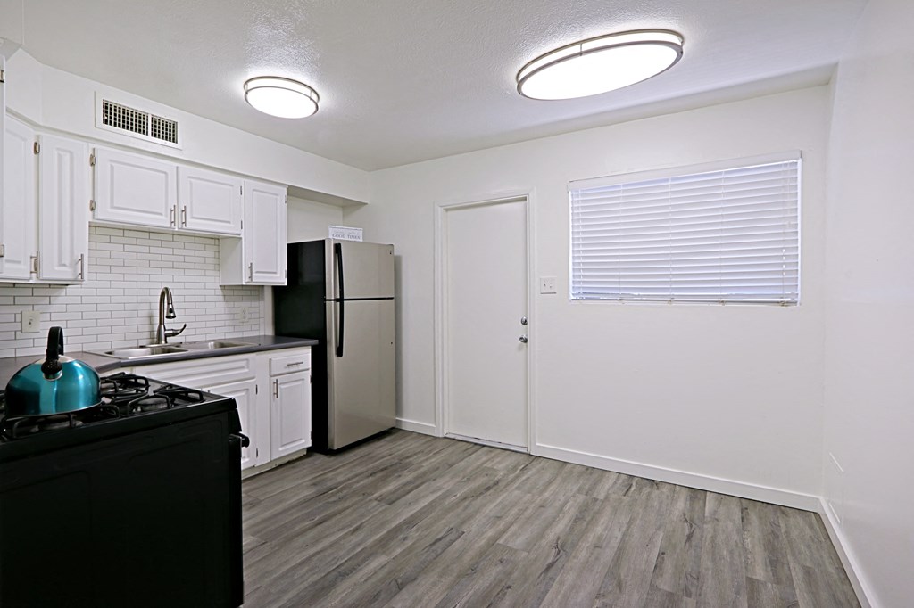 an empty kitchen with white cabinets and a black refrigerator