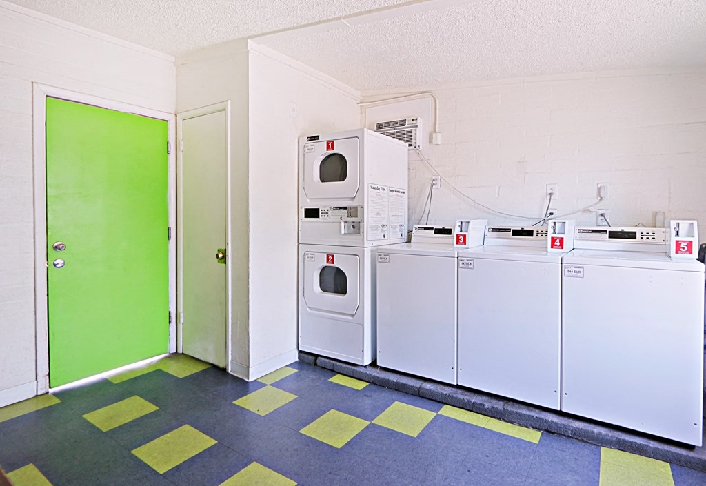a row of washers and dryers in a room with green door