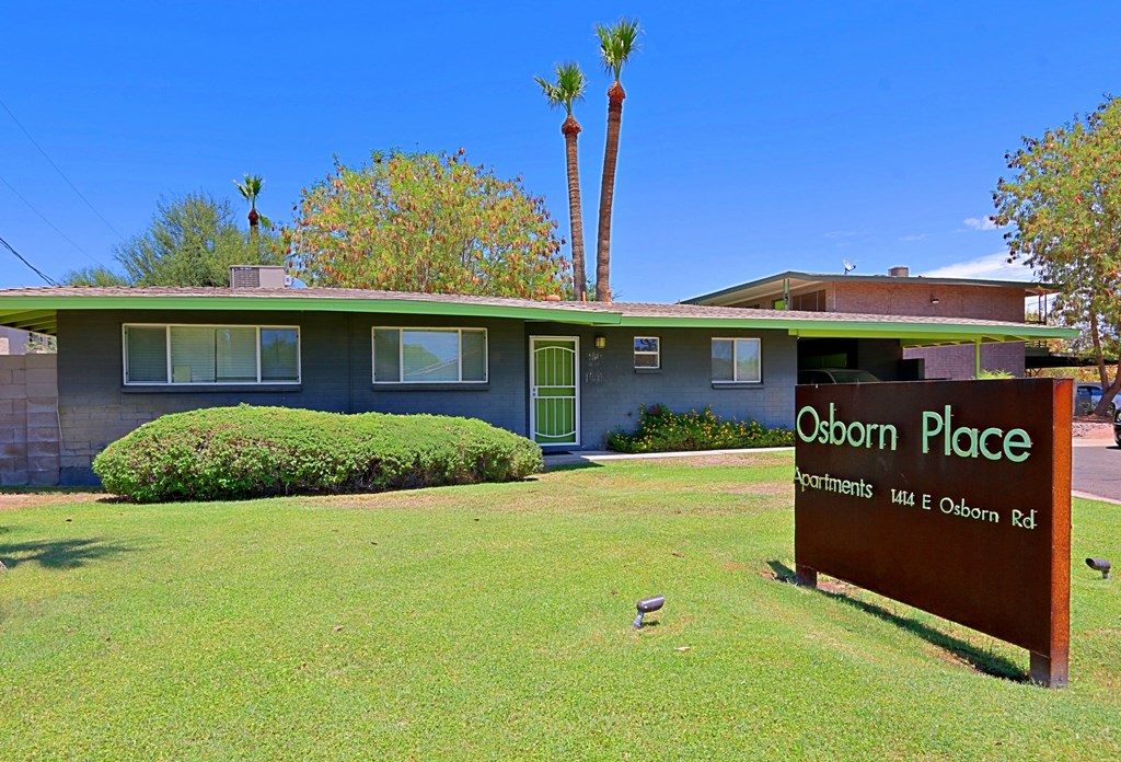 a sign in front of a house with palm trees