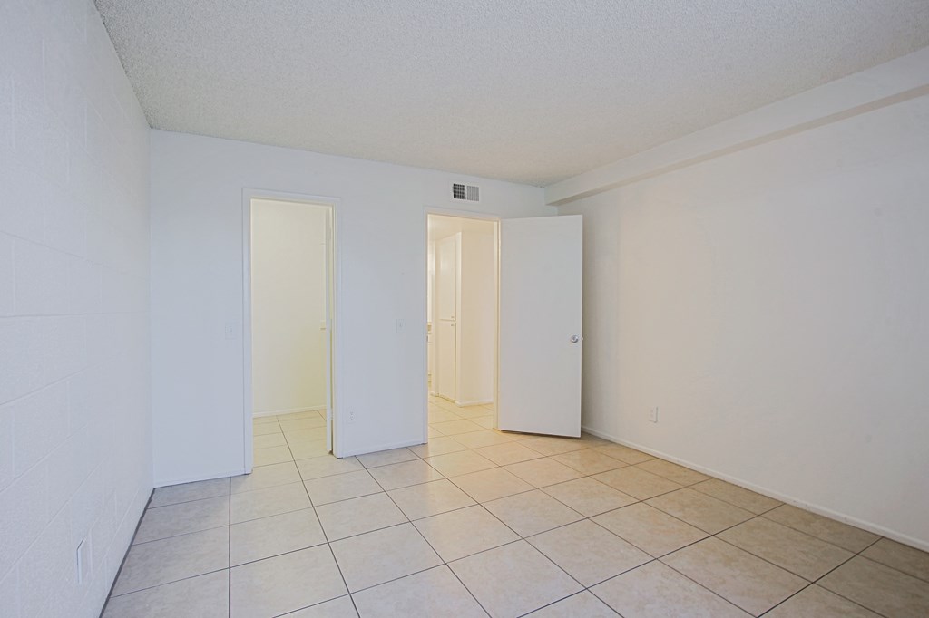 an empty living room with a tiled floor and white walls