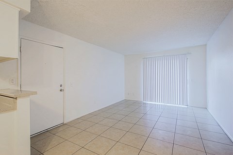 the living room and dining room of an apartment with a tiled floor