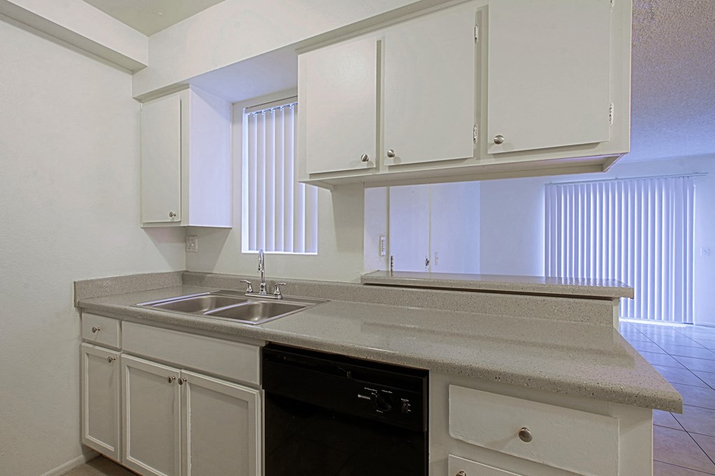 an empty kitchen with white cabinets and a sink