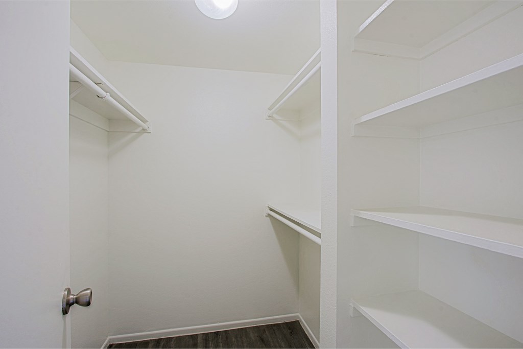 a walk in closet with white shelves and a door