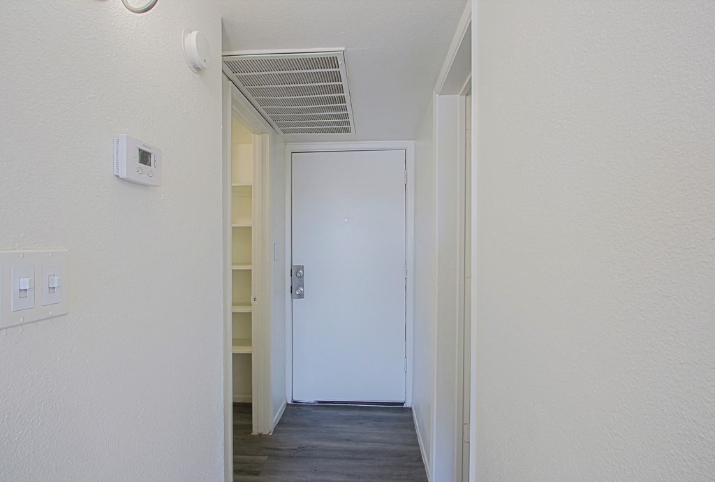 an empty hallway with a white door and a closet