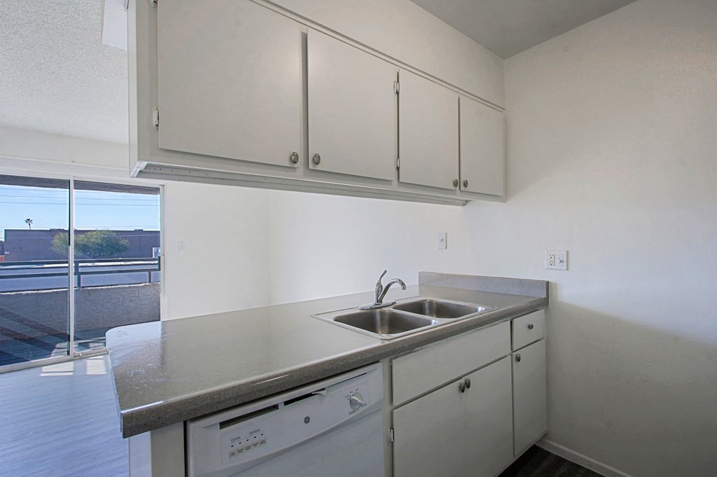 an empty kitchen with white cabinets and a sink