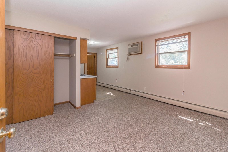 an empty living room with a door to a closet and a window