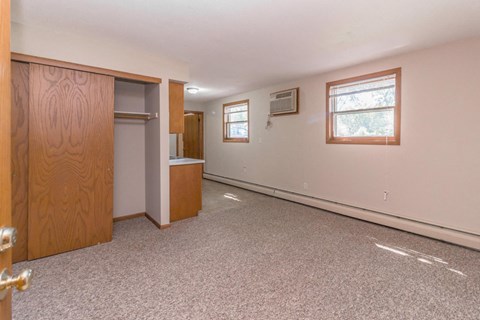 an empty living room with a door to a closet and a window
