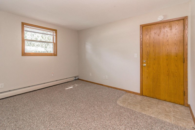 an empty room with a wooden door and a window
