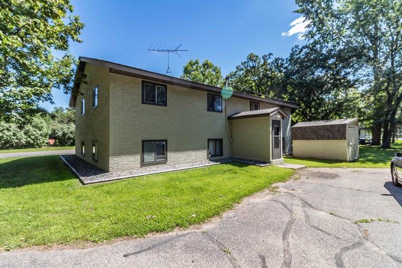 a tan house with a driveway and a green lawn