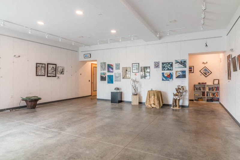 a room with paintings and art on the walls and a cement floor