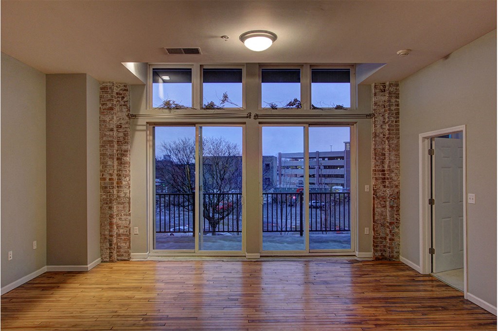 an empty living room with large windows and a door to a balcony