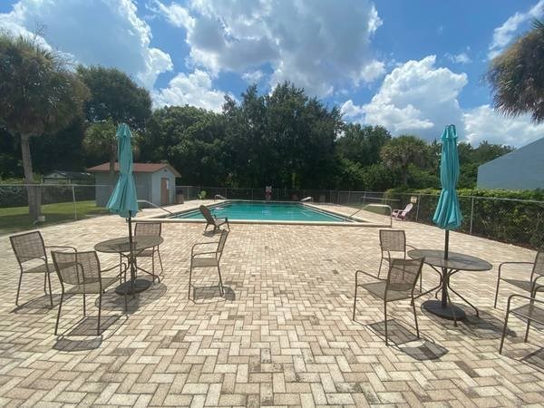 A patio with a table and chairs overlooking a pool.